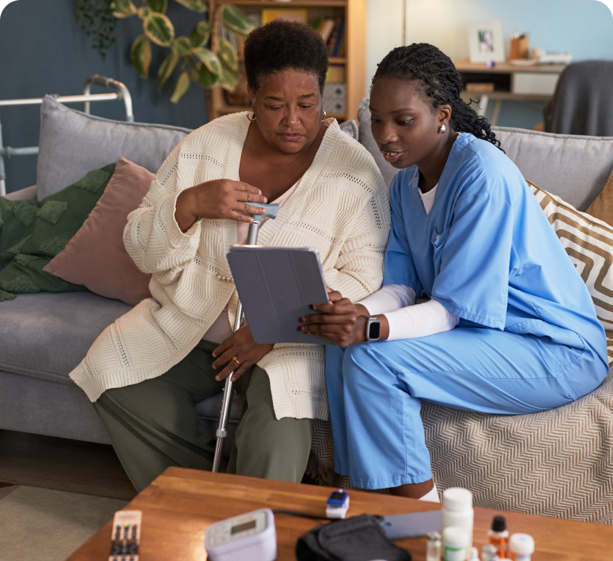 Caregiver and elderly woman reviewing tablet data